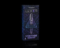 A boxed pen set standing upright on a black reflective surface. The package is dark blue with a geometric pattern and glowing neon-style text reading 'LUMEN' and 'VANTAGE'.