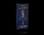 A boxed pen set standing upright on a black reflective surface. The package is dark blue with a geometric pattern and glowing neon-style text reading 'LUMEN' and 'VANTAGE'.