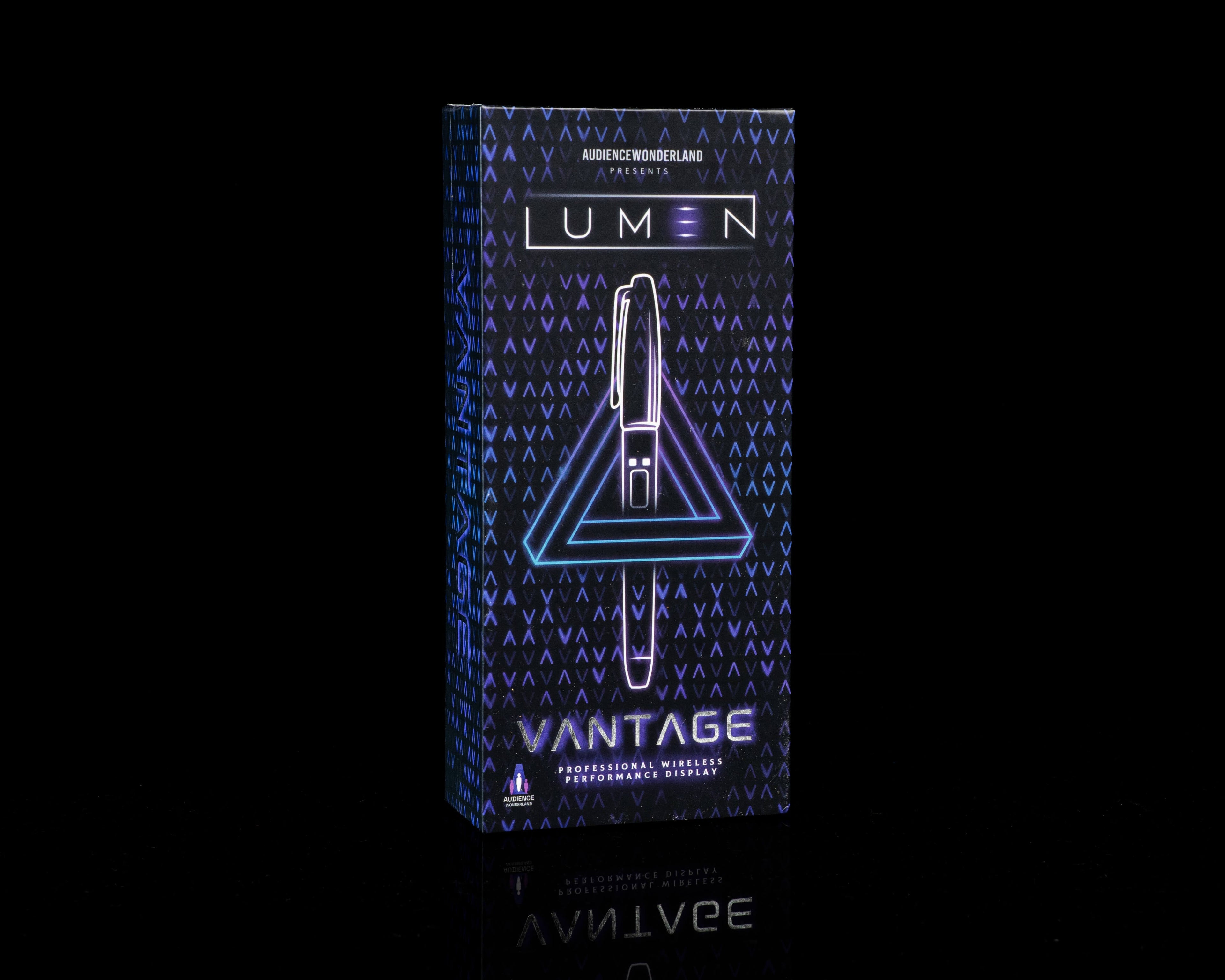 A boxed pen set standing upright on a black reflective surface. The package is dark blue with a geometric pattern and glowing neon-style text reading 'LUMEN' and 'VANTAGE'.