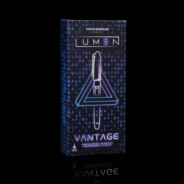 A boxed pen set standing upright on a black reflective surface. The package is dark blue with a geometric pattern and glowing neon-style text reading 'LUMEN' and 'VANTAGE'.